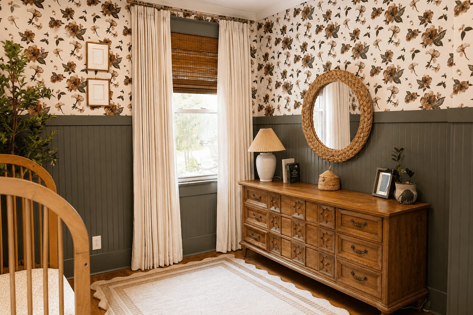 Room with floral wallpaper, window with curtains, wooden dresser with mirror, lamp, and decorative items, and a rug on the floor.