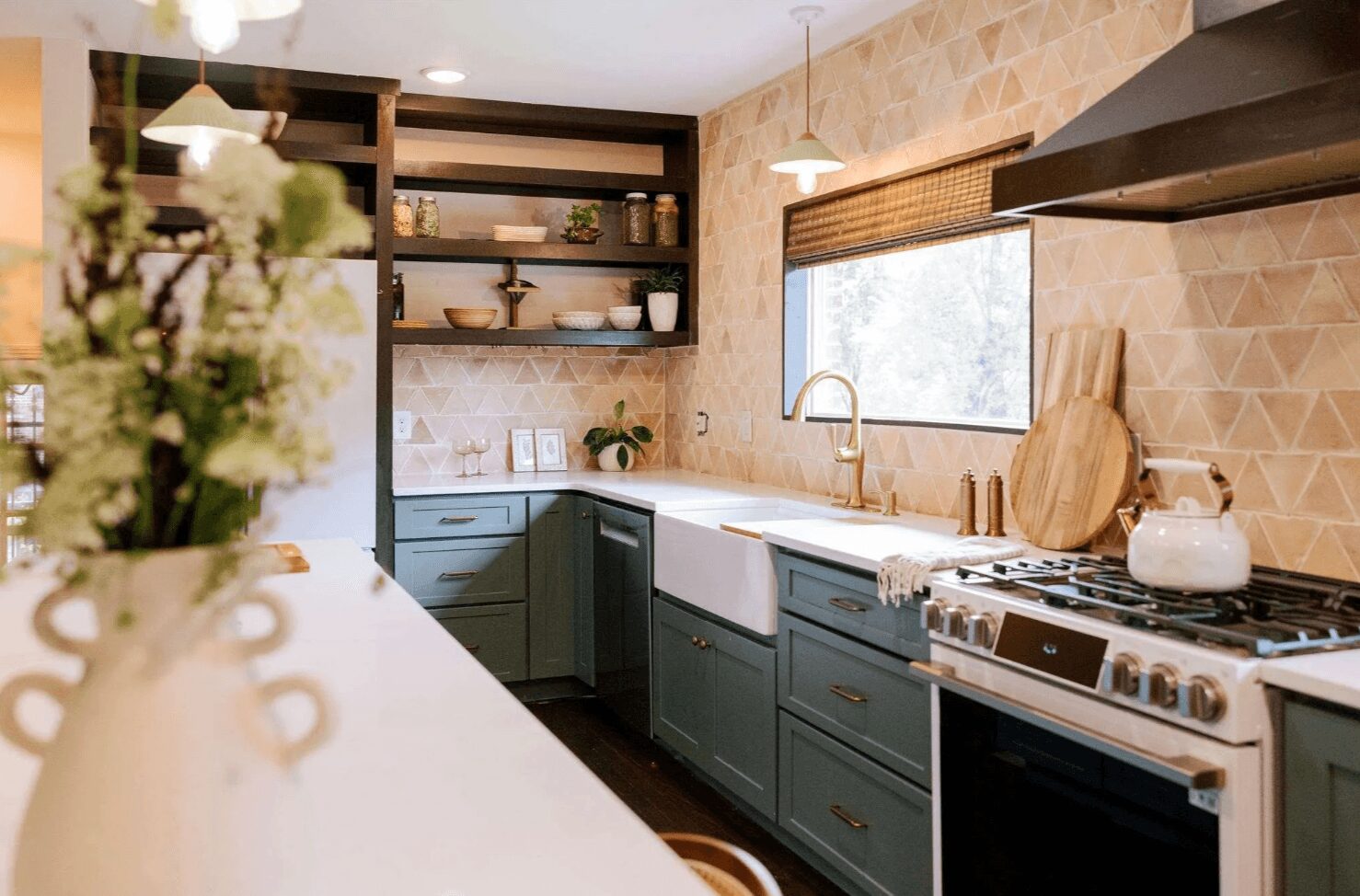 Kitchen with blue cabinets, a white sink, window, stove, and open shelves with dishes, decorated with plants and wooden accents.