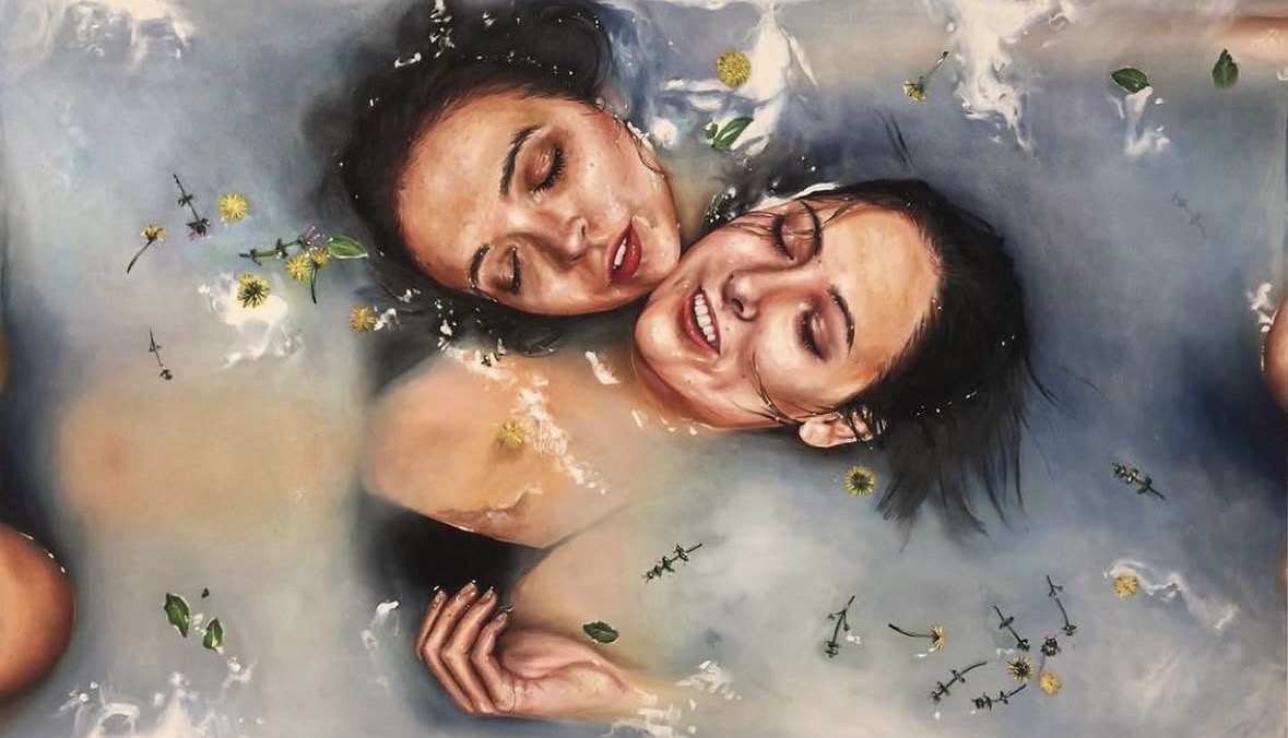 Two women with closed eyes and relaxed expressions float in water with floating flowers and leaves.