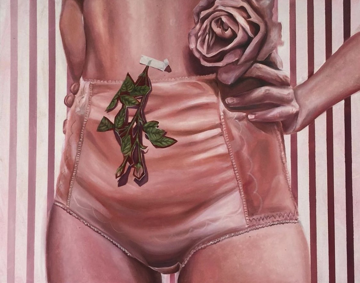 Close-up of a person wearing pink shorts, holding a rose, with striped background.