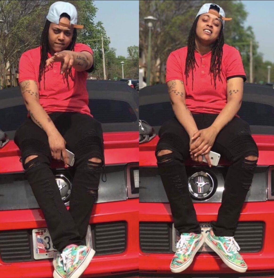 Person sitting on a red car, wearing a red shirt, black pants, and colorful sneakers, outdoors on a sunny day.