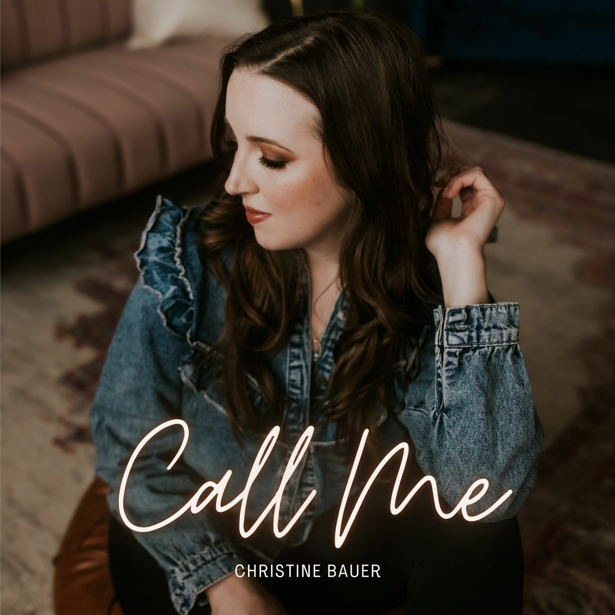 A woman with long dark hair in a denim jacket sits indoors, with text 'Call Me' and 'Christine Bauer' overlayed.