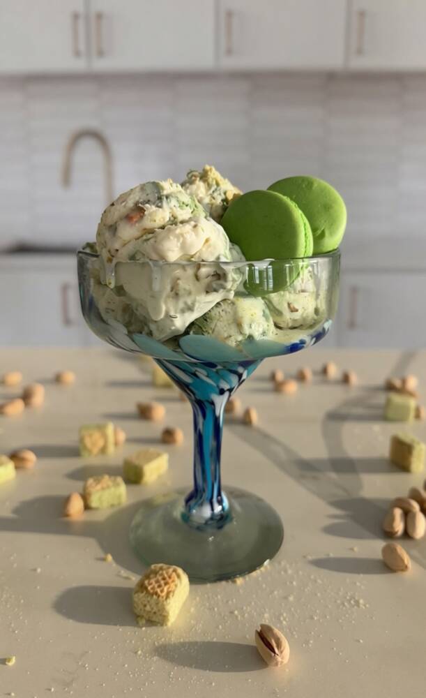 Ice cream in a glass with green apples, on a table with scattered nuts, kitchen background, bright lighting.