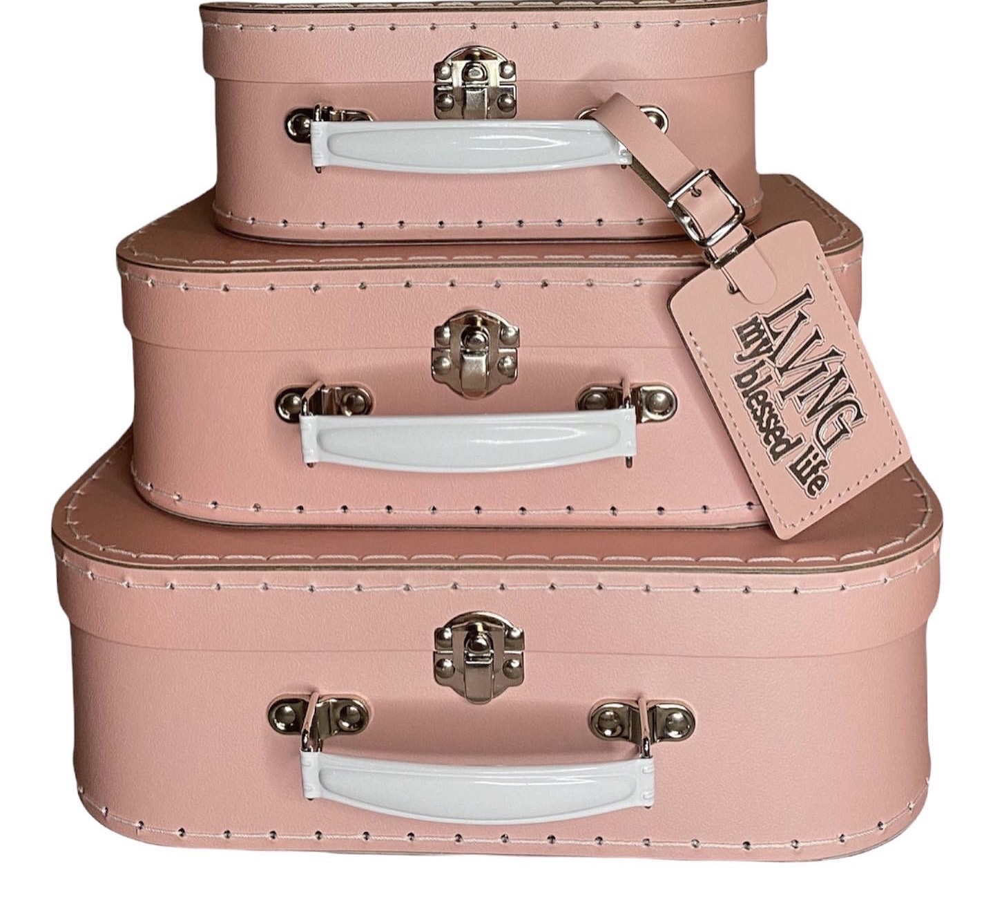 Three pink suitcases stacked, with white handles and a luggage tag, against a plain background.
