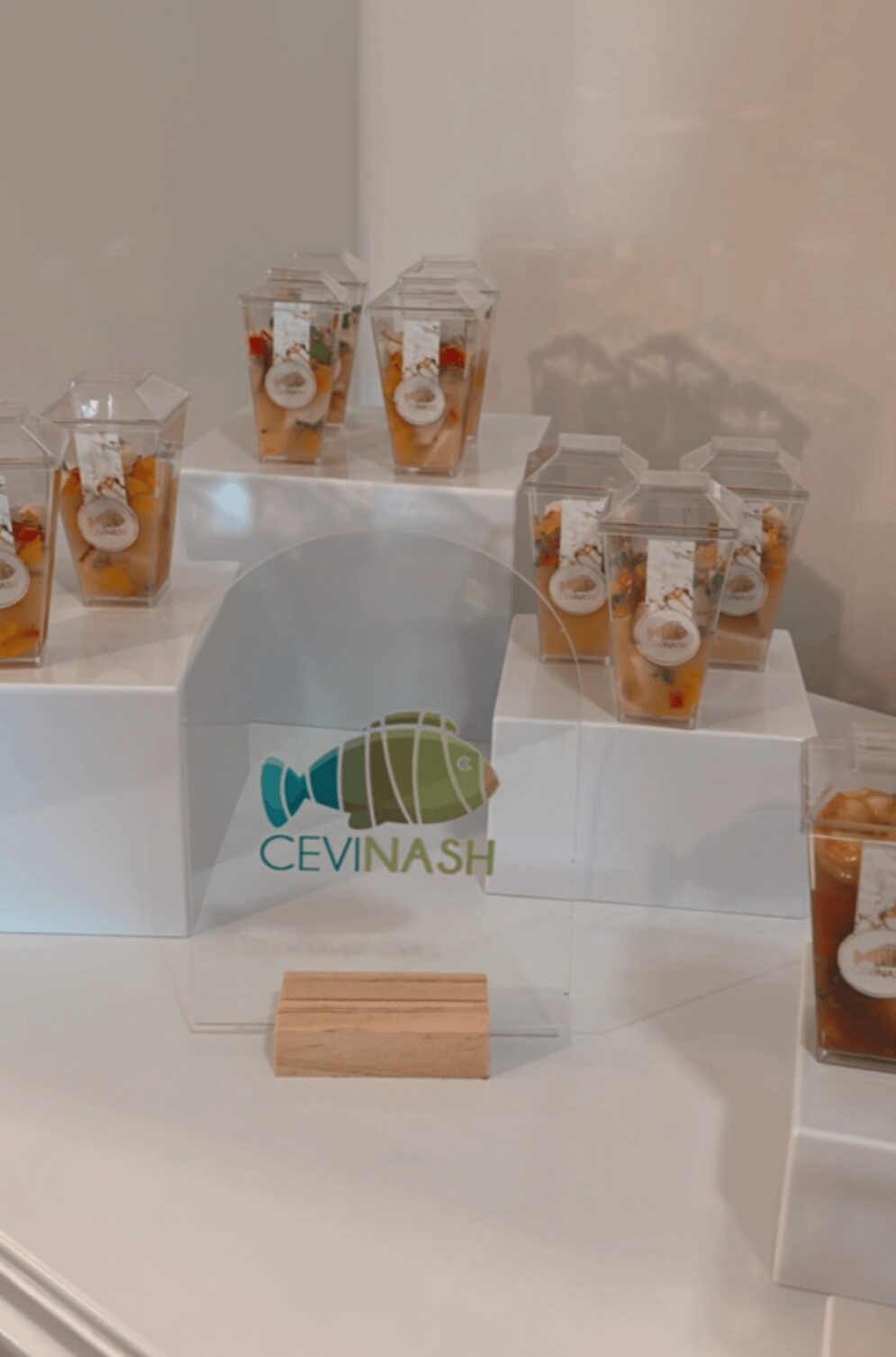 Display of small cups with orange and white contents on clear stands, with a CEVINASH logo on the front, against a plain background.