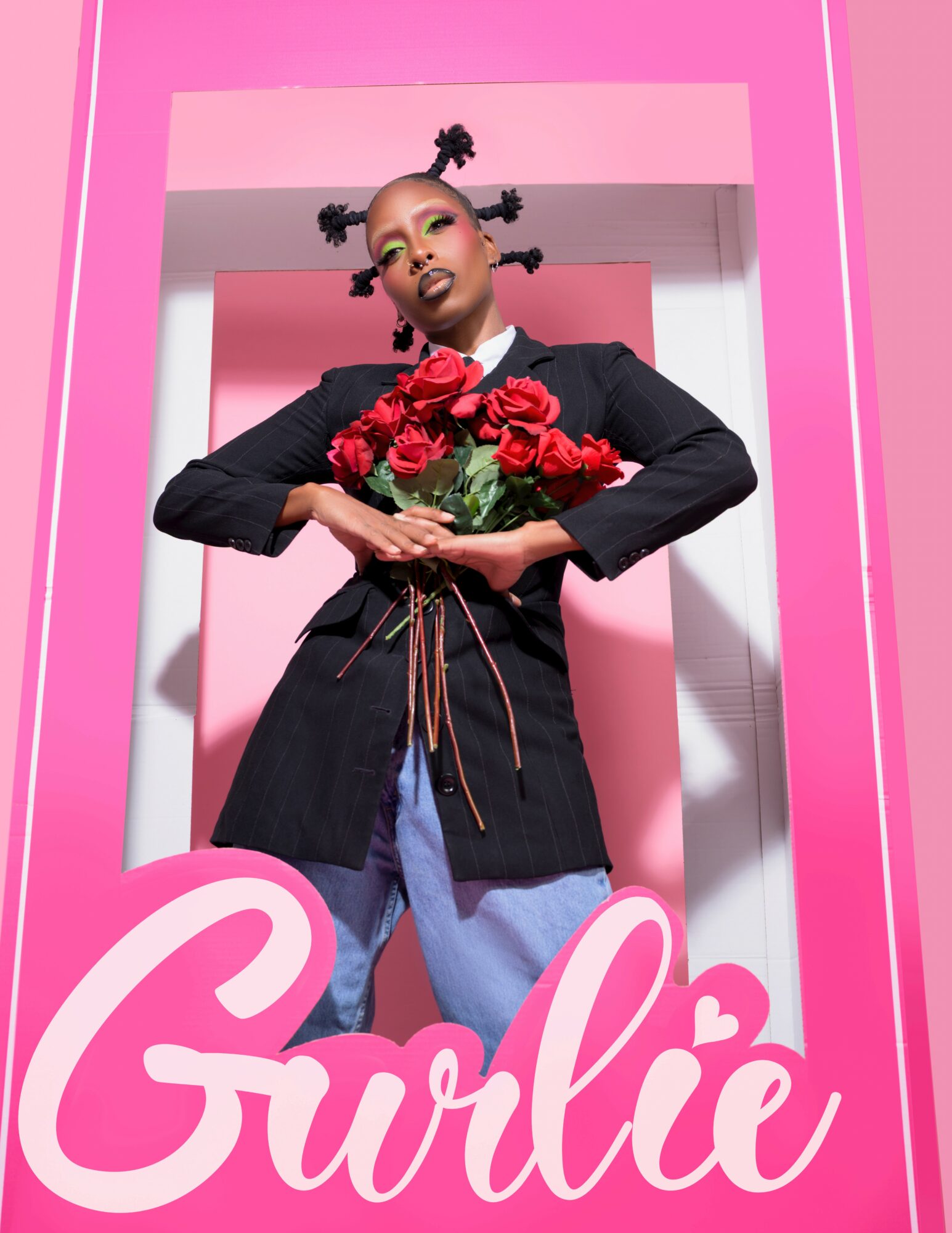 Person with styled hair holding a bouquet of red roses, standing in front of a pink background with pink and white framing.