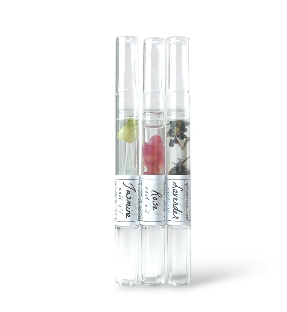 Three transparent test tubes with labels, containing different plants or flowers, stand upright against a white background.