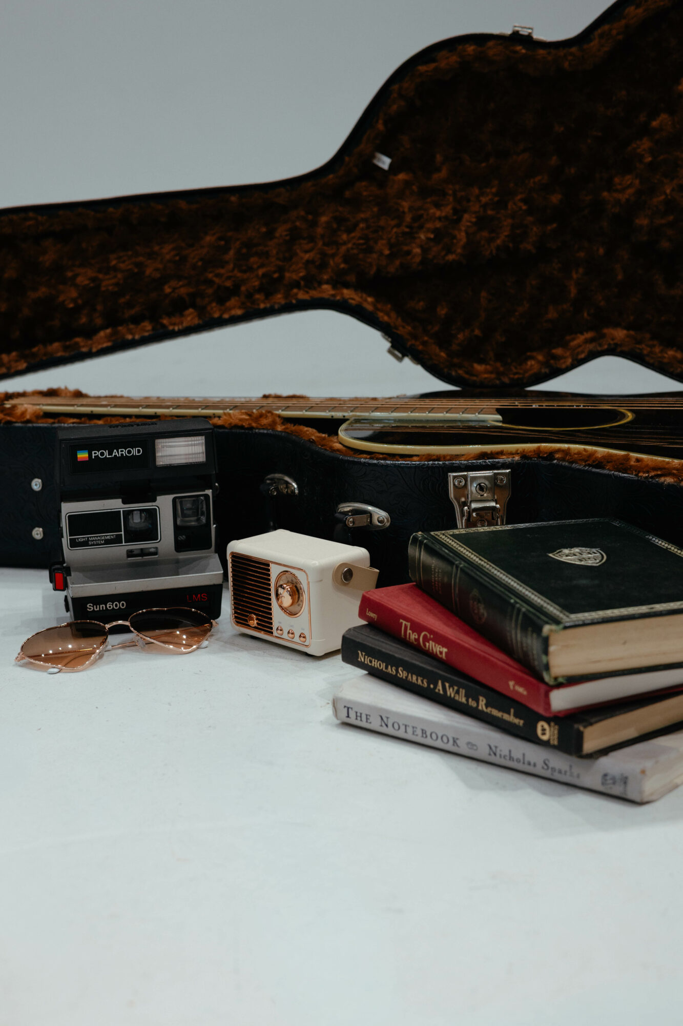 Guitar case, books, and electronic device on a white surface.