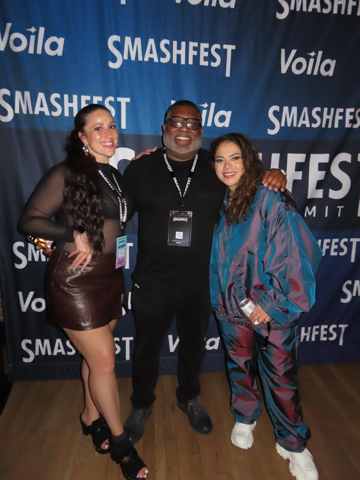 Three people standing together in front of a blue backdrop with 'SMASHFEST' and 'Voila' logos, smiling at the camera.