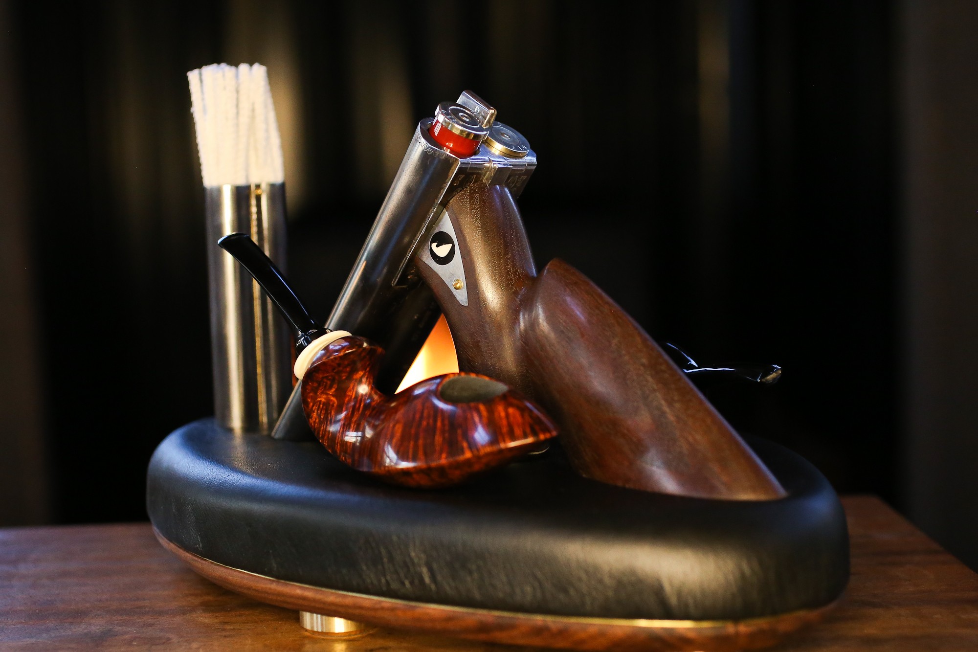 A novelty bicycle-shaped bottle opener with a wooden finish, mounted on a black base, on a wooden surface.