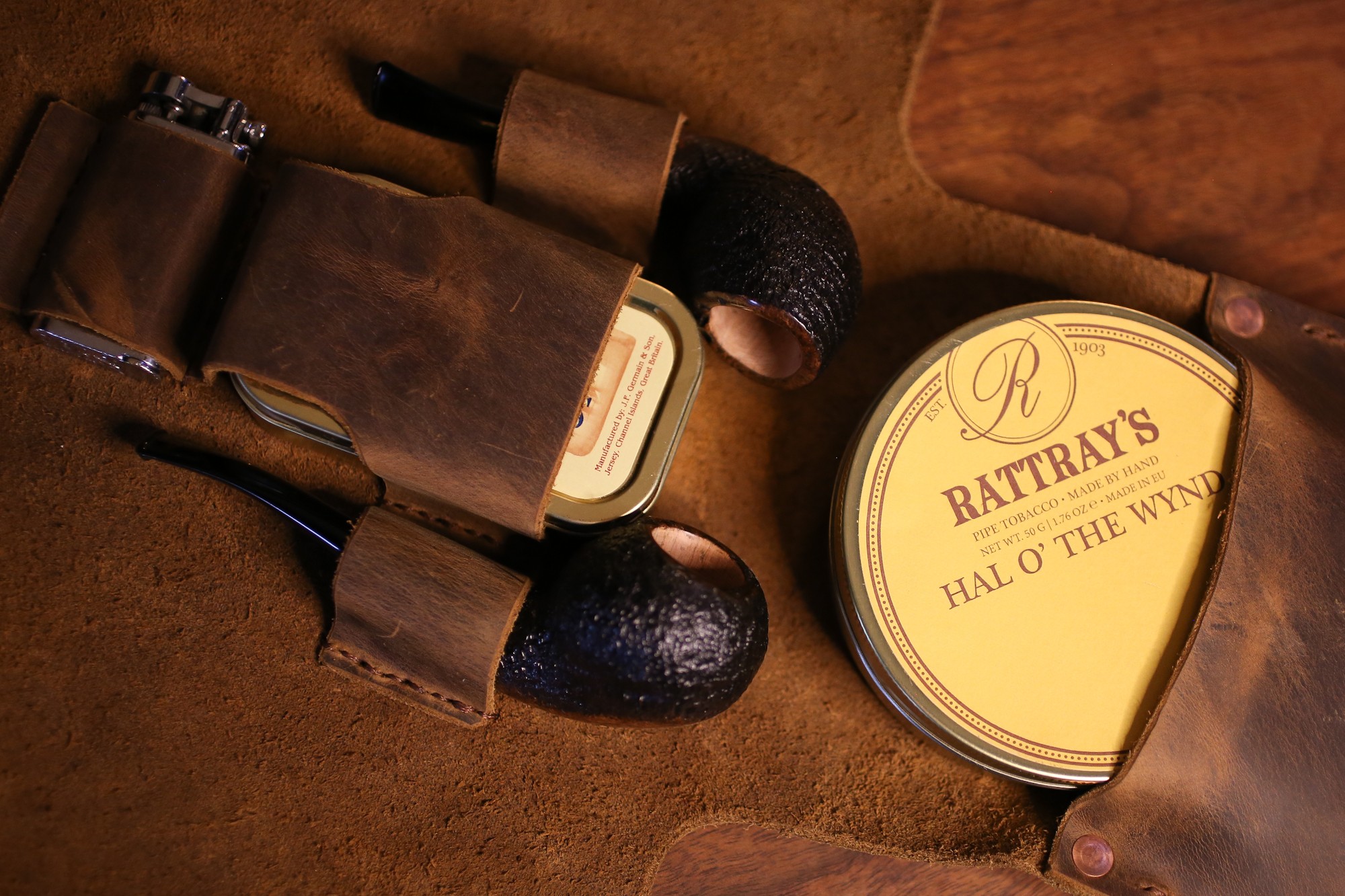 Leather belt, a round tin labeled 'Rattray's Hal o' the Wynd,' and a leather item on a brown surface.