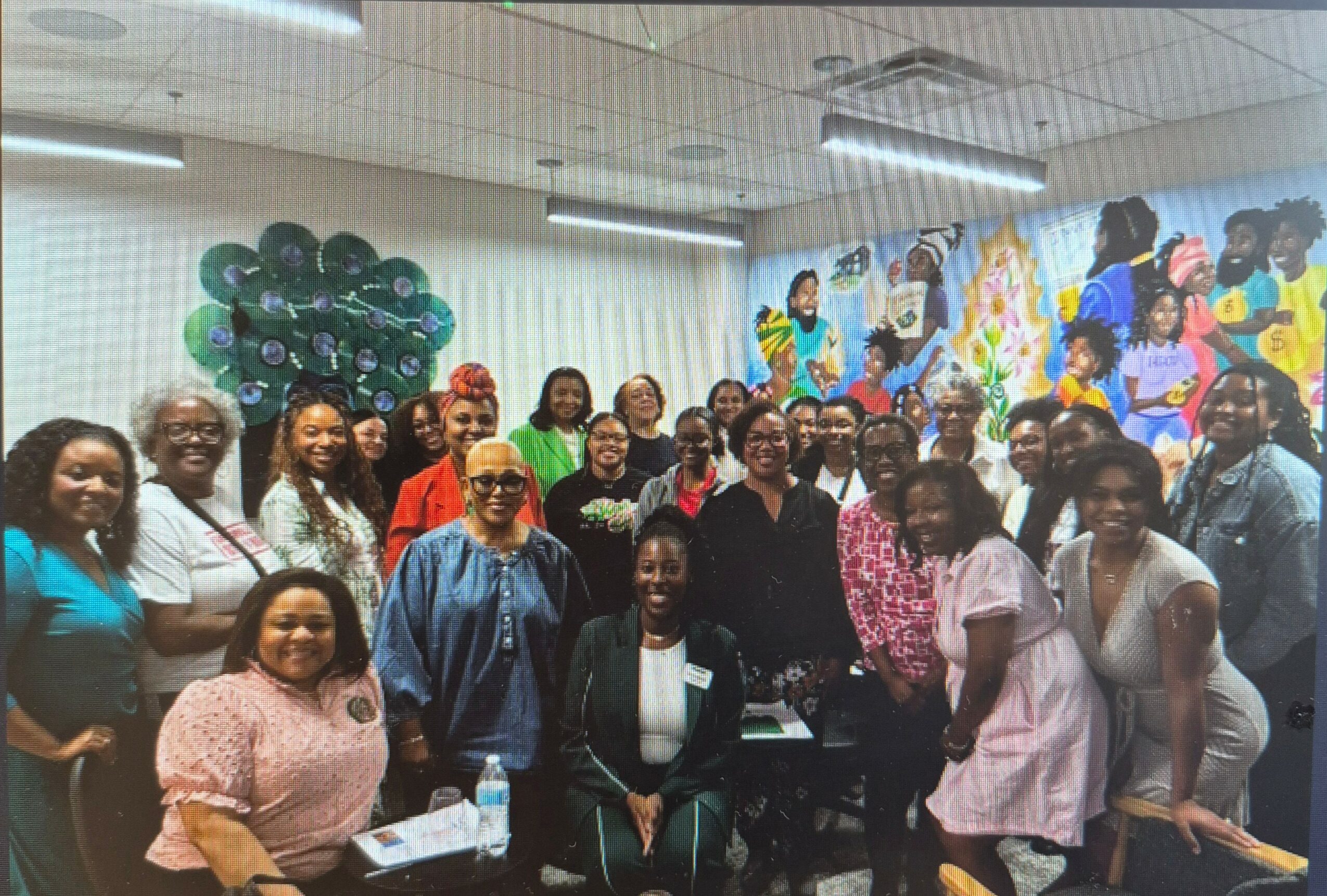 Group of people gathered in a room with colorful decorations and balloons, smiling for a photo.