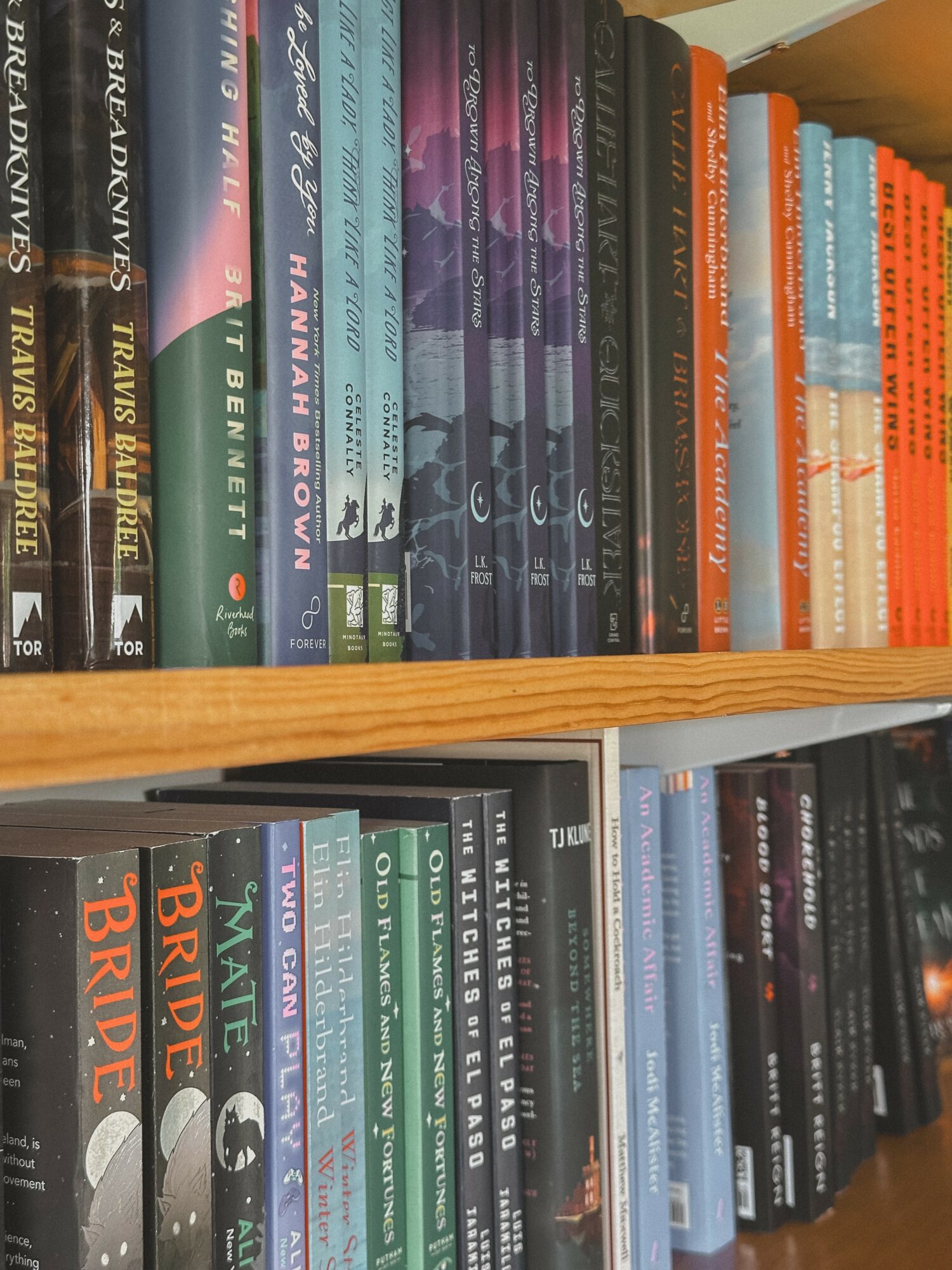 Bookshelves filled with colorful books arranged vertically on wooden shelves.