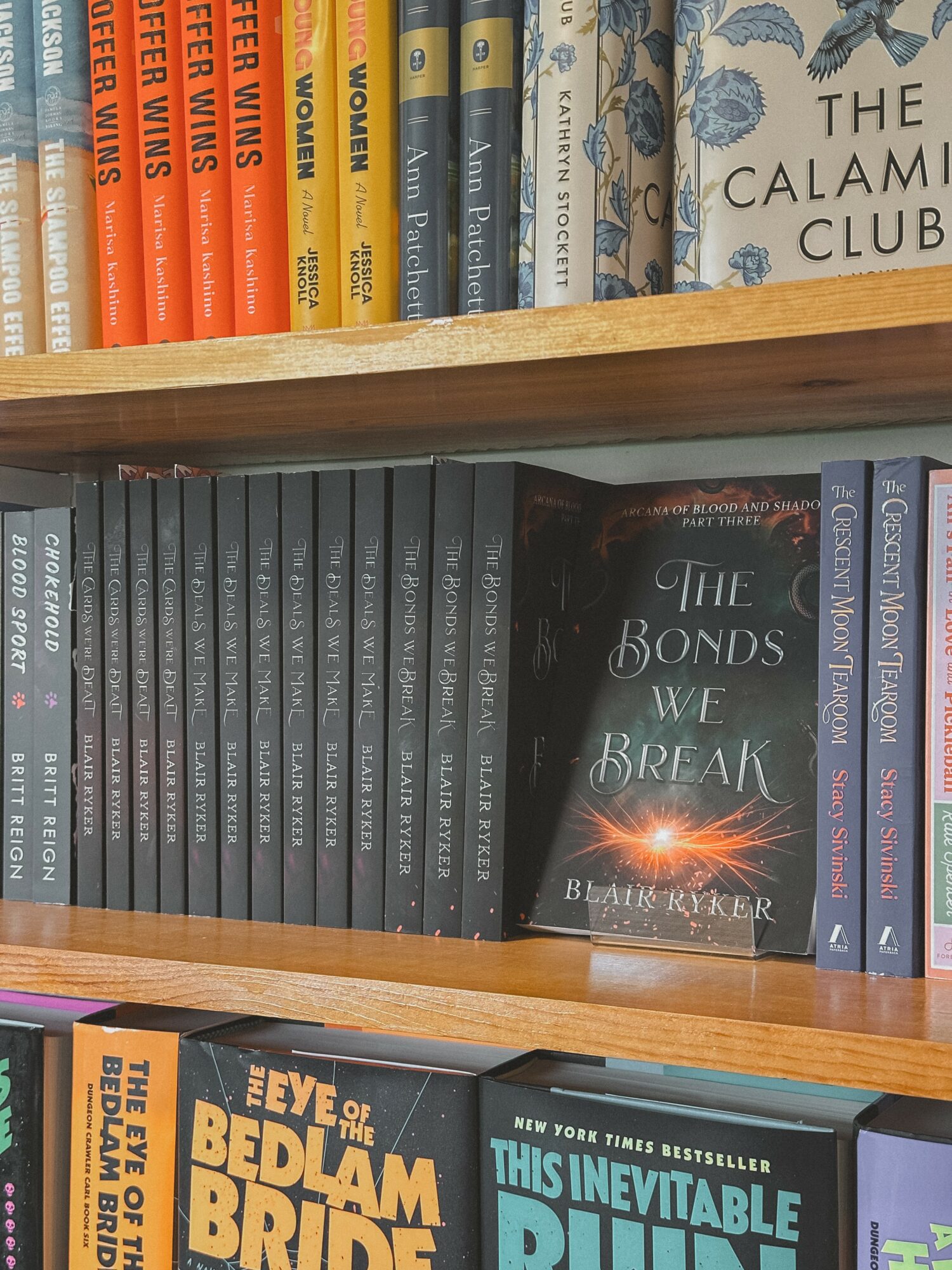 Bookshelves filled with colorful and dark books, including a visible copy of 'The Bonds We Break' by Blake Kyler.
