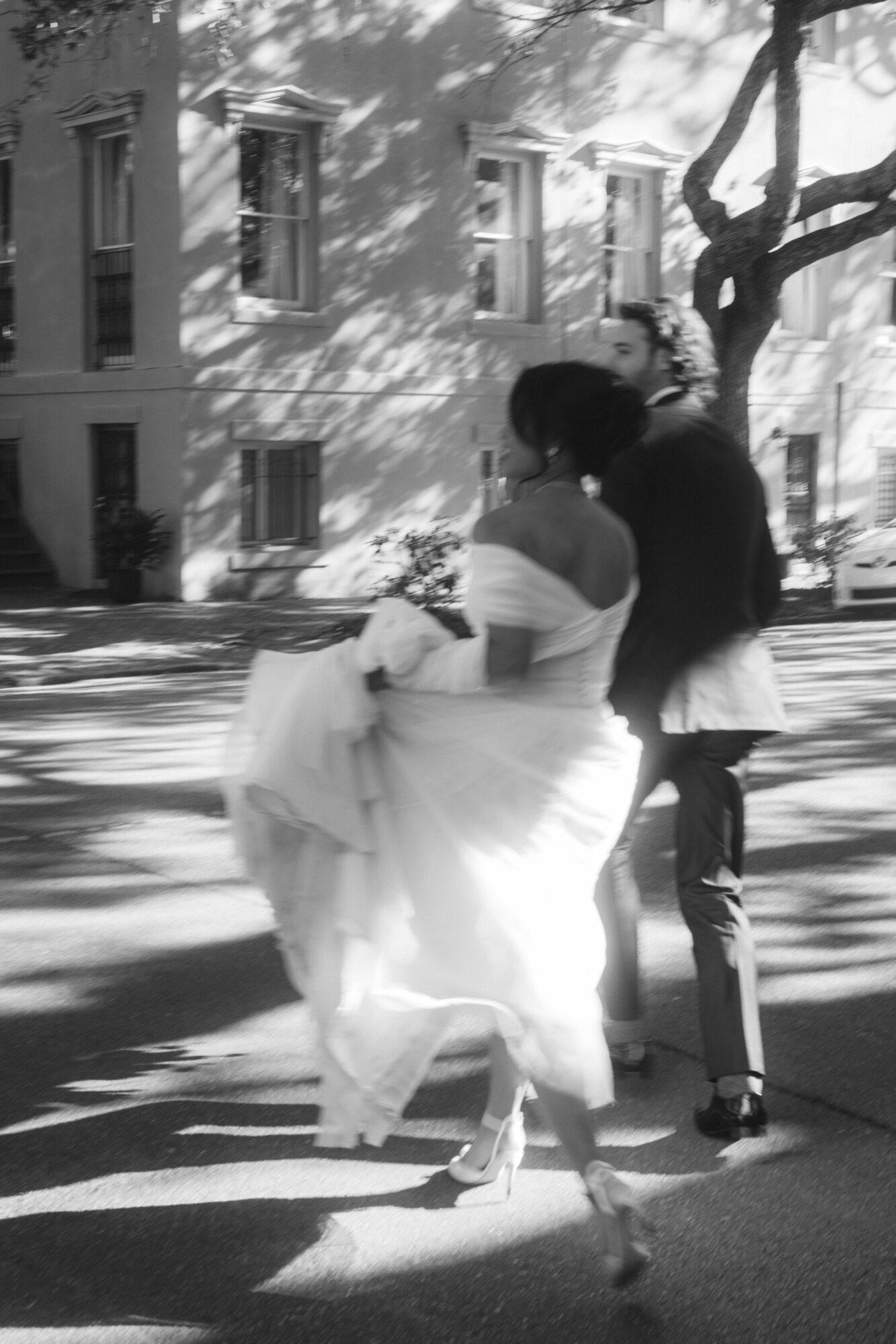 A couple dancing outdoors near a tree, with shadows and a building in the background.