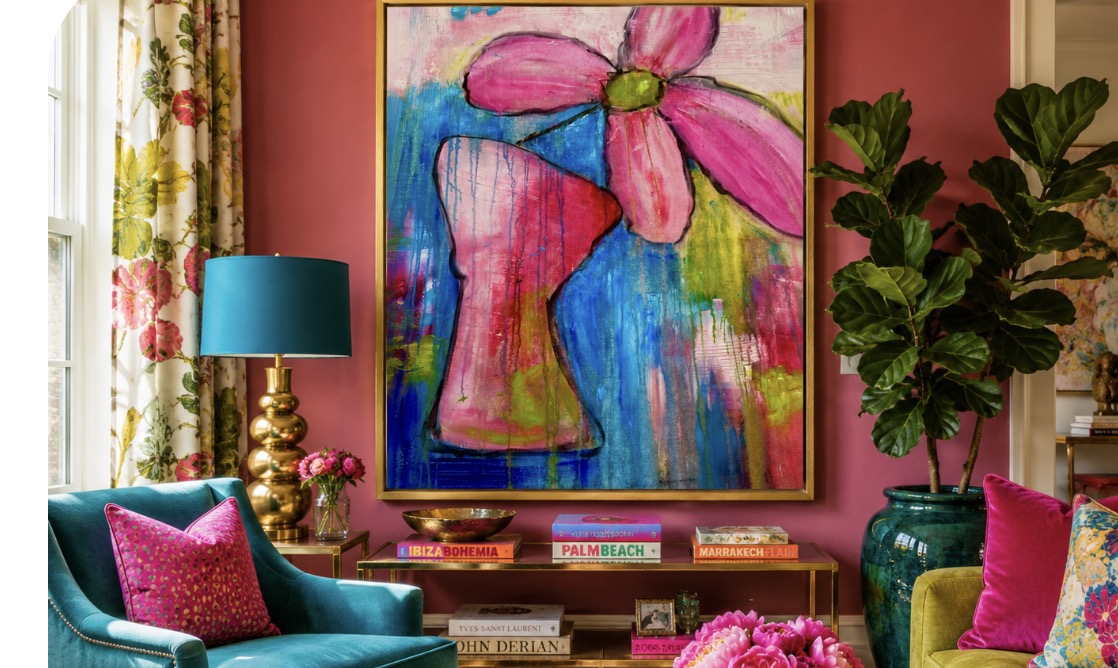 Living room with colorful artwork, teal armchair, pink pillows, large green plant, and decorative lamp.