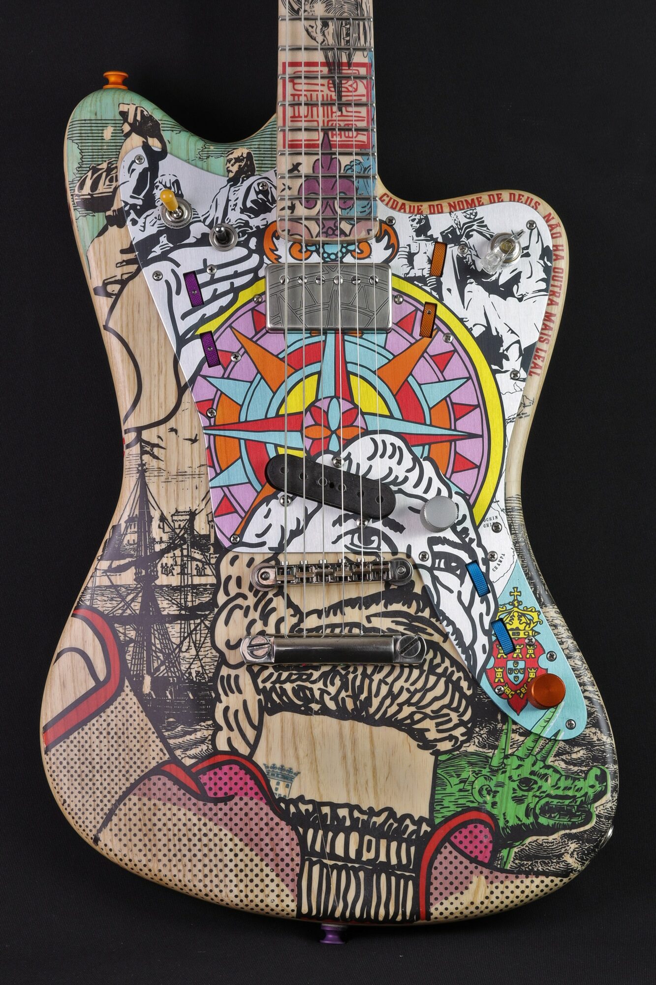 Colorful guitar with various illustrations including animals, a compass, and abstract designs, on a black background.