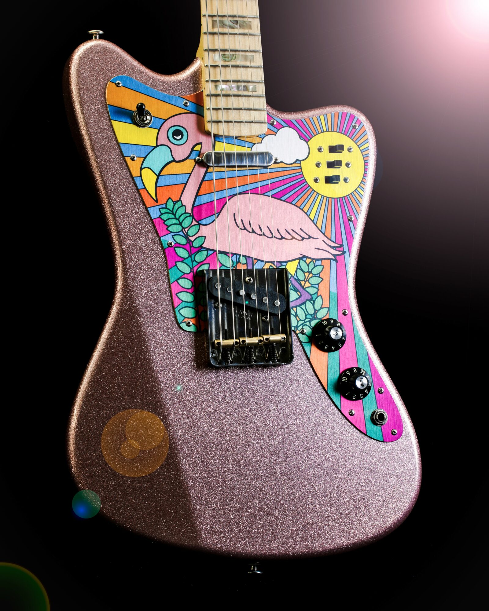Guitar with colorful, abstract artwork on the body, featuring a pink flamingo, stripes, and geometric patterns.