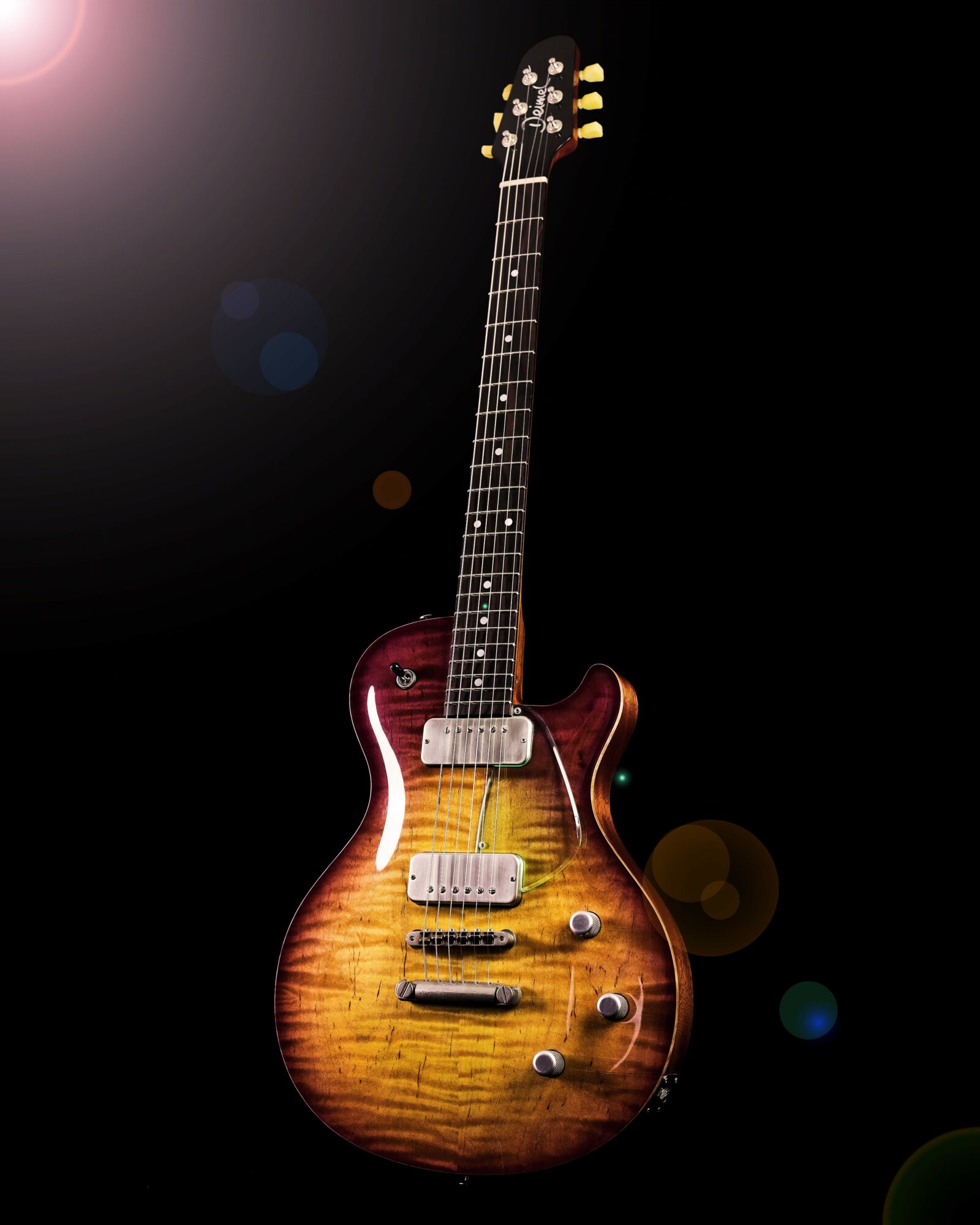 Electric guitar with a sunburst finish and two humbucker pickups, set against a dark background with lens flare effects.