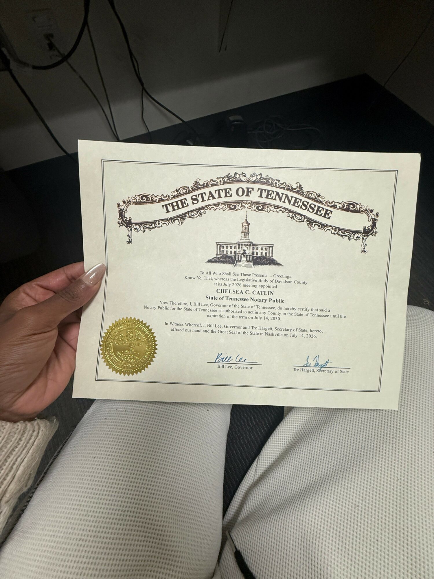 Person holding a certificate with a gold seal, text, and signatures, rotated 90 degrees clockwise.