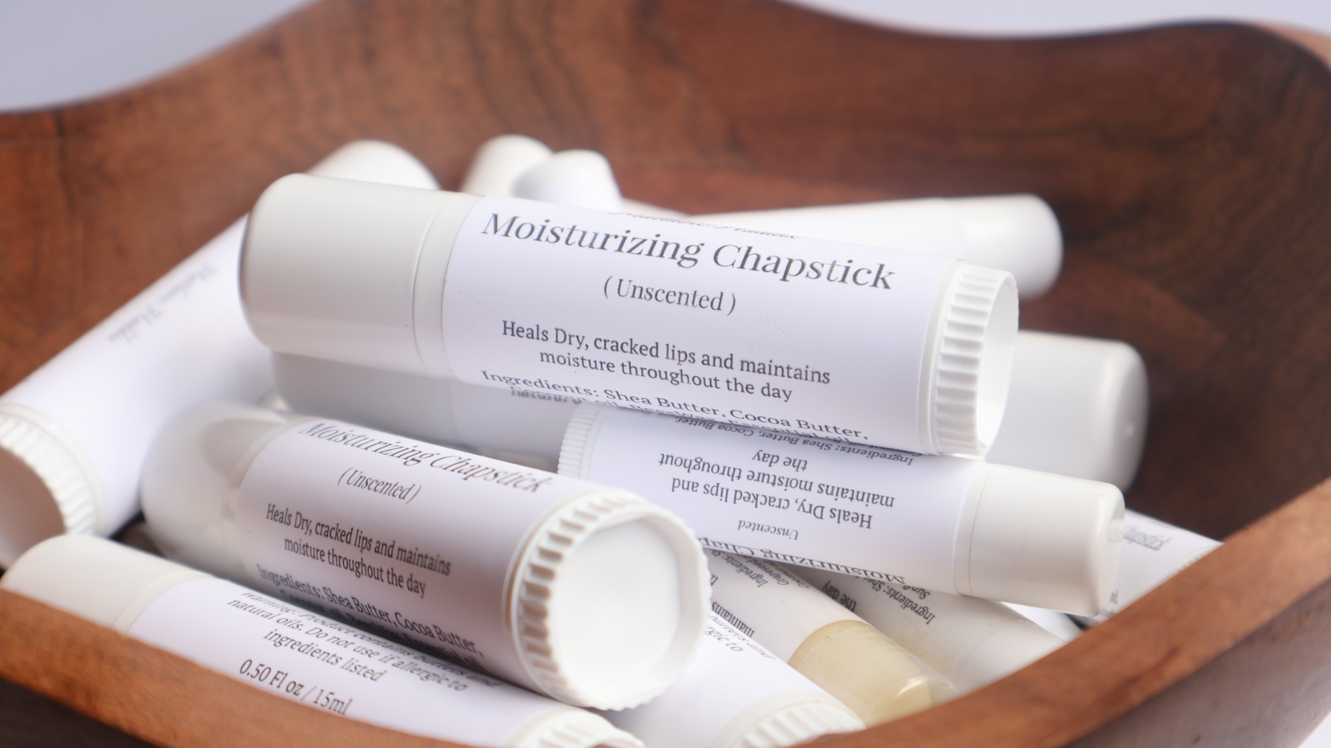 Several white moisturizing chapstick tubes in a wooden container.