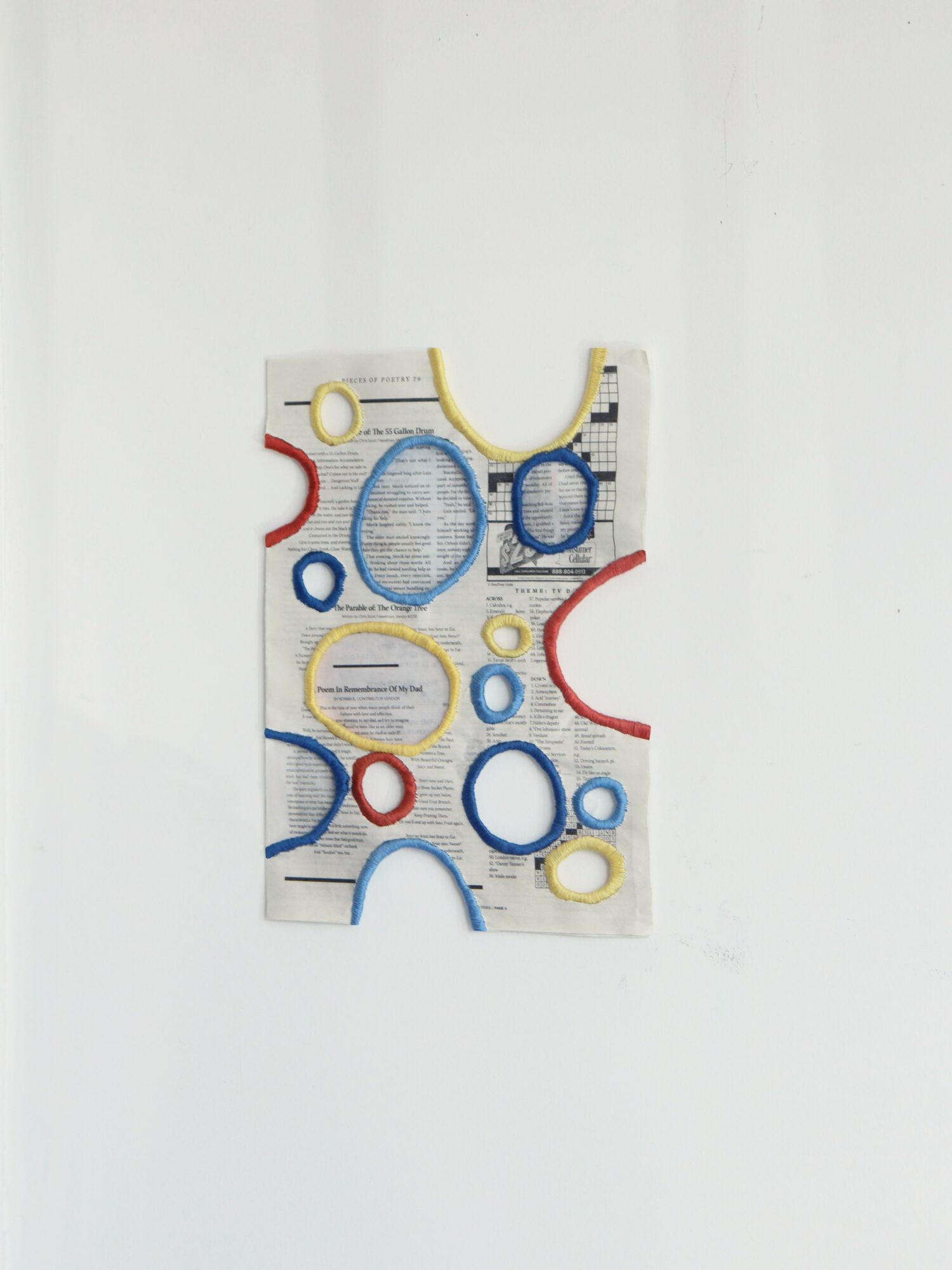 Rectangular object with colorful circular cutouts and lines, hanging against a plain white background.