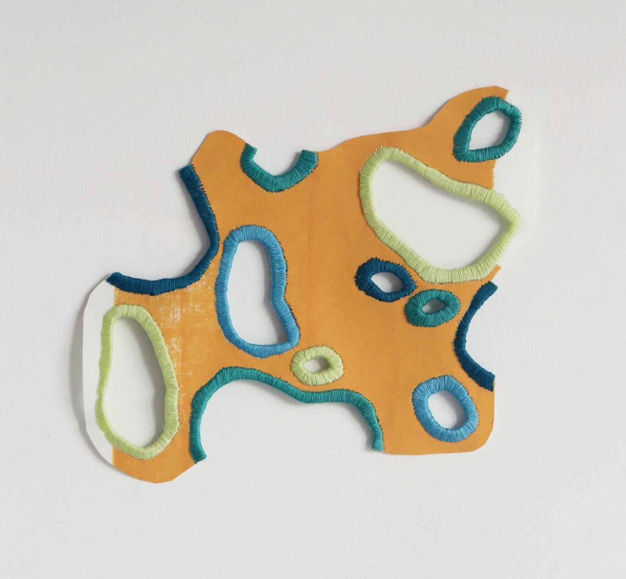 Colorful fabric piece with cutouts and stitched edges on a white background.