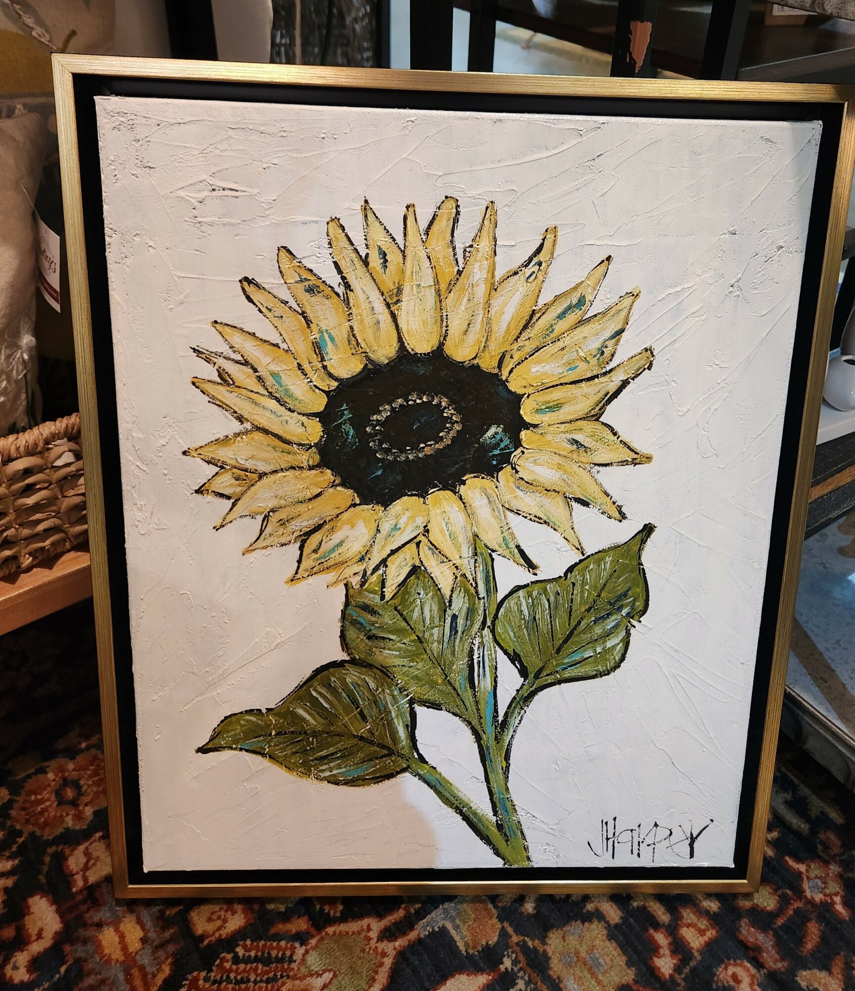 Painting of a sunflower with yellow petals, green leaves, and a dark center, signed in the bottom right corner.