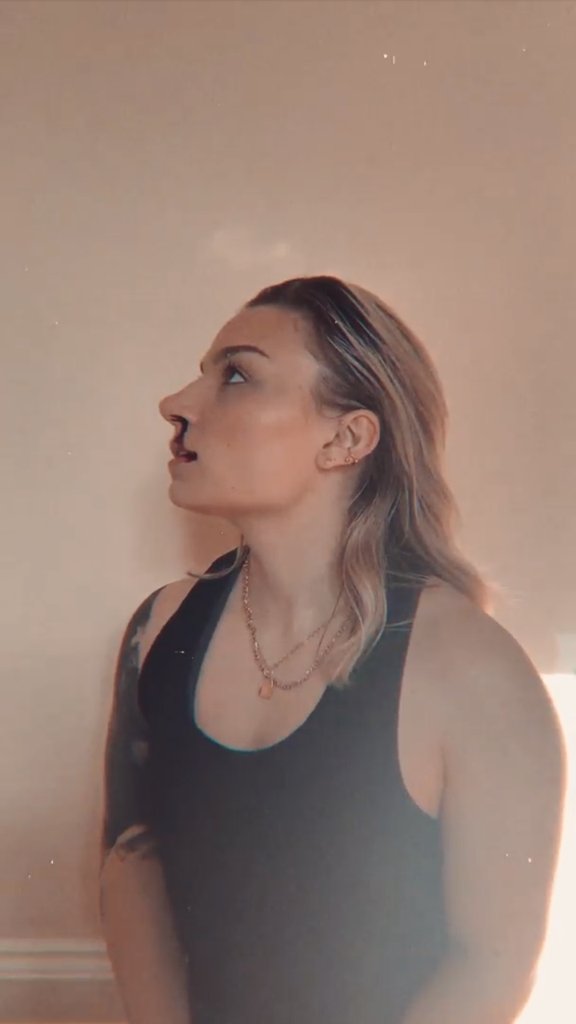 Side profile of a woman with long hair wearing a black sleeveless top, looking to the left.