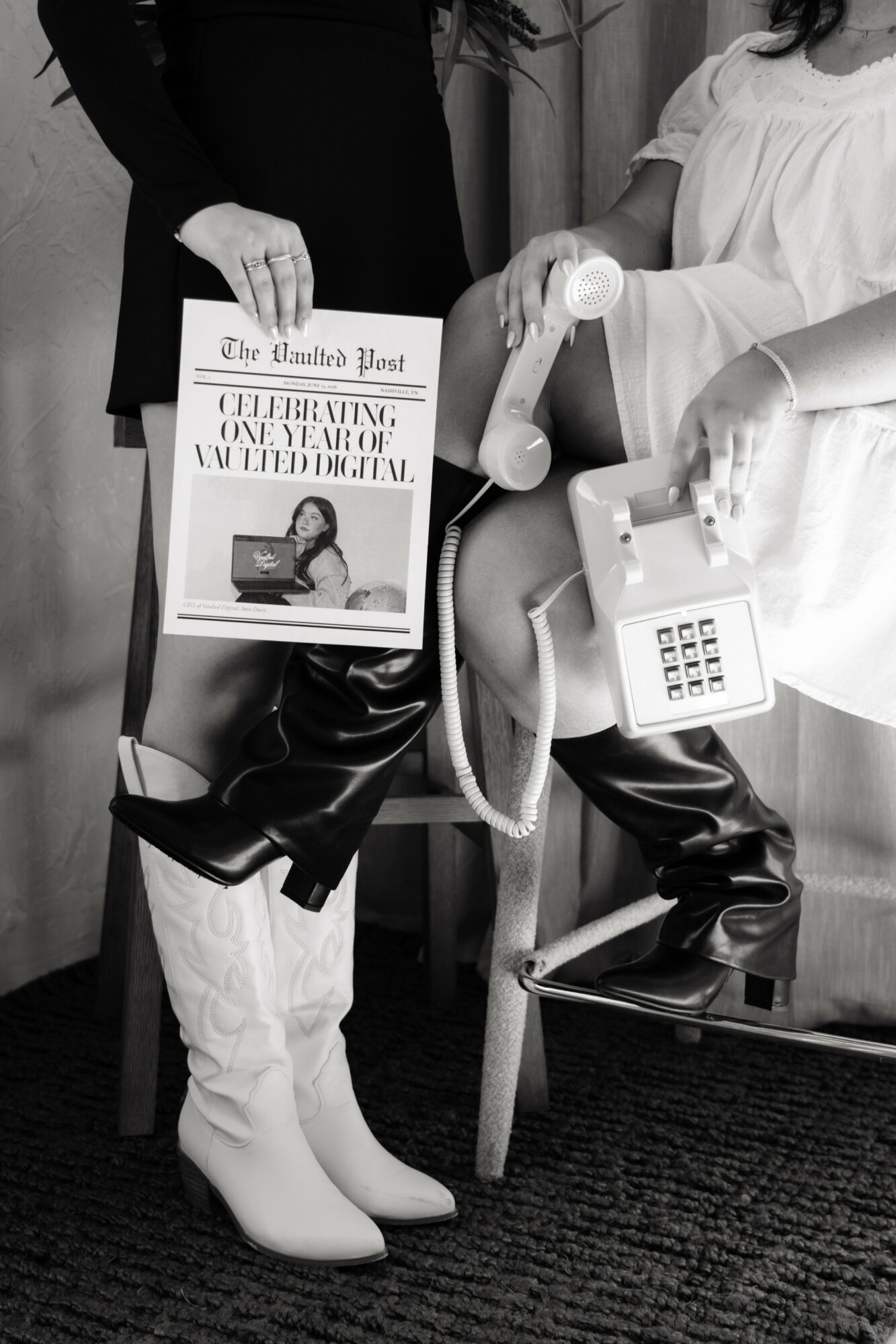 Person holding a newspaper and a shoe, another person sitting with a telephone, in a medical setting.