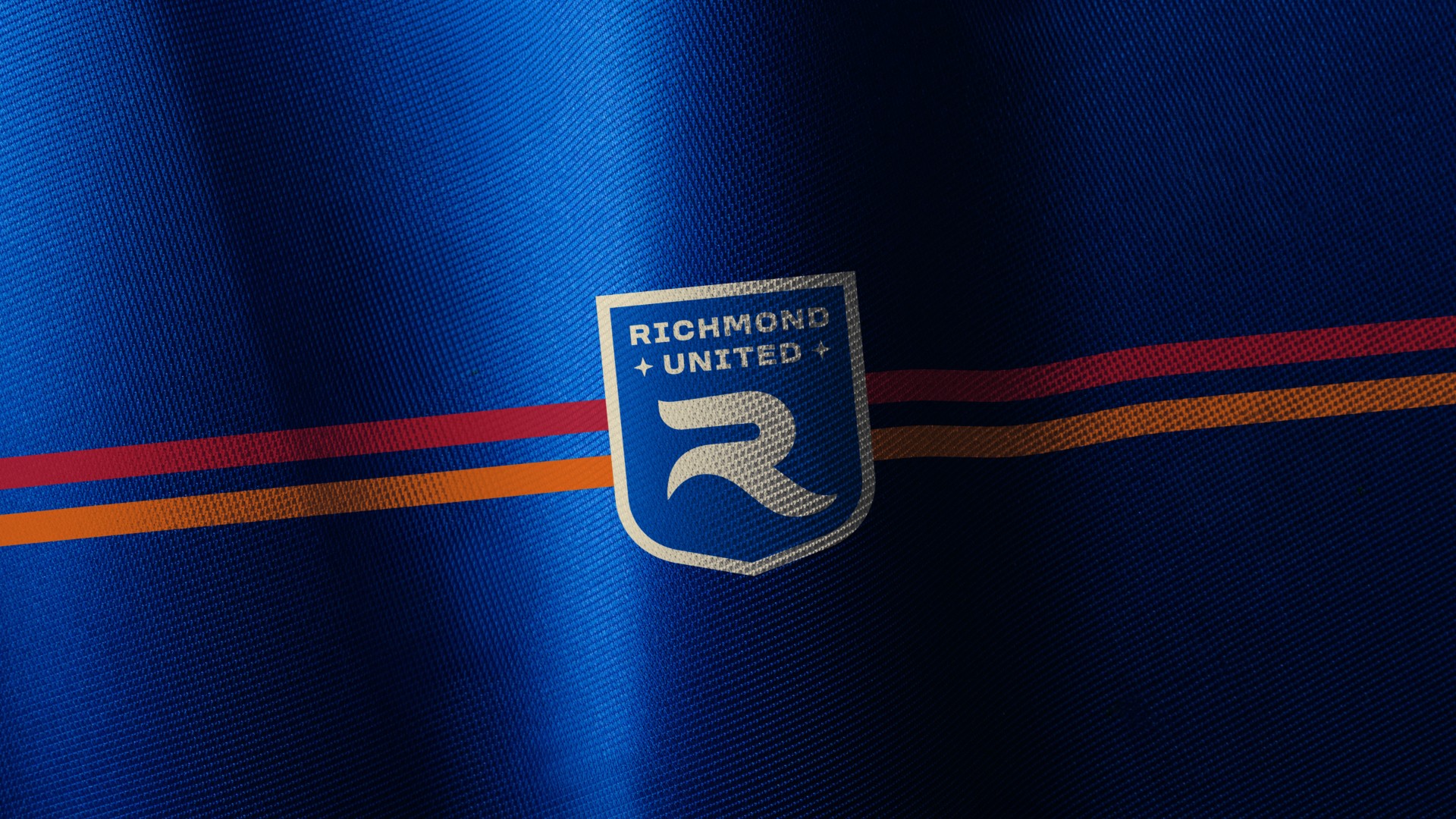 Close-up of a fabric with a Richmond United logo and red and orange stripes.
