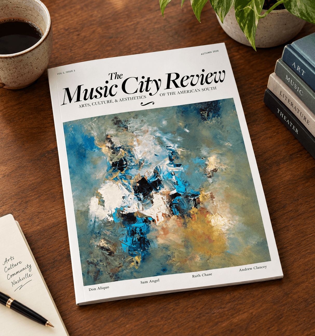 Magazine titled 'The Music City Review' on a wooden table with a colorful abstract cover, surrounded by a cup, books, and a pen.