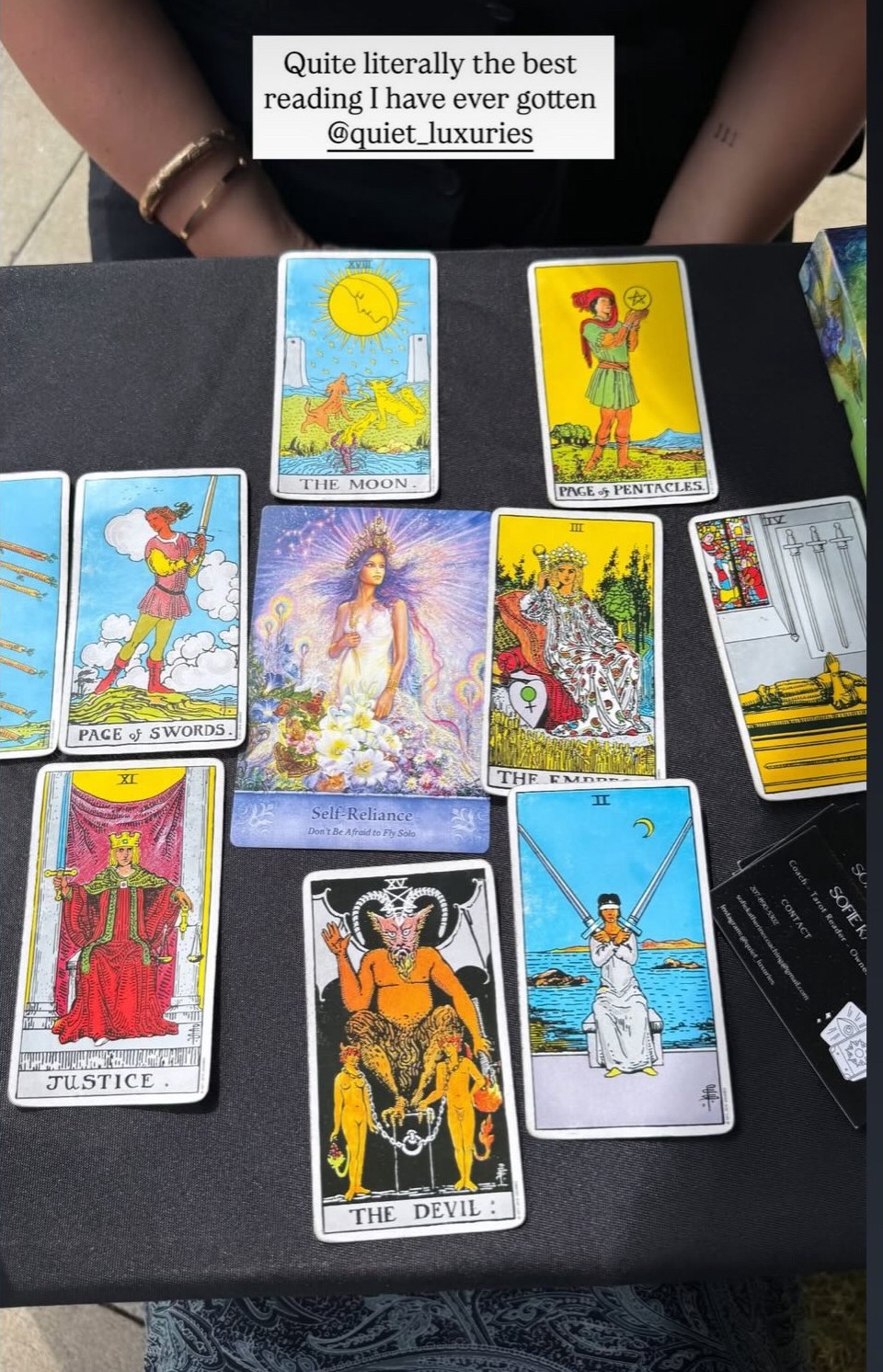 A spread of tarot cards on a black surface with a person's hands in the background, and a quote at the top.