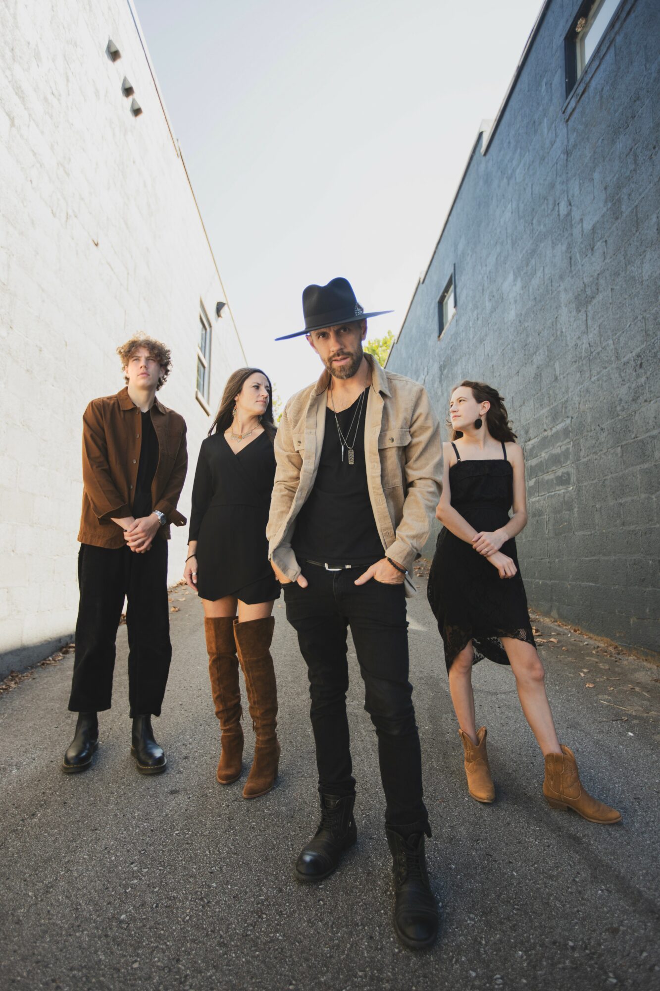 Four people standing in an alleyway between white and dark blue buildings, posing for a photo.