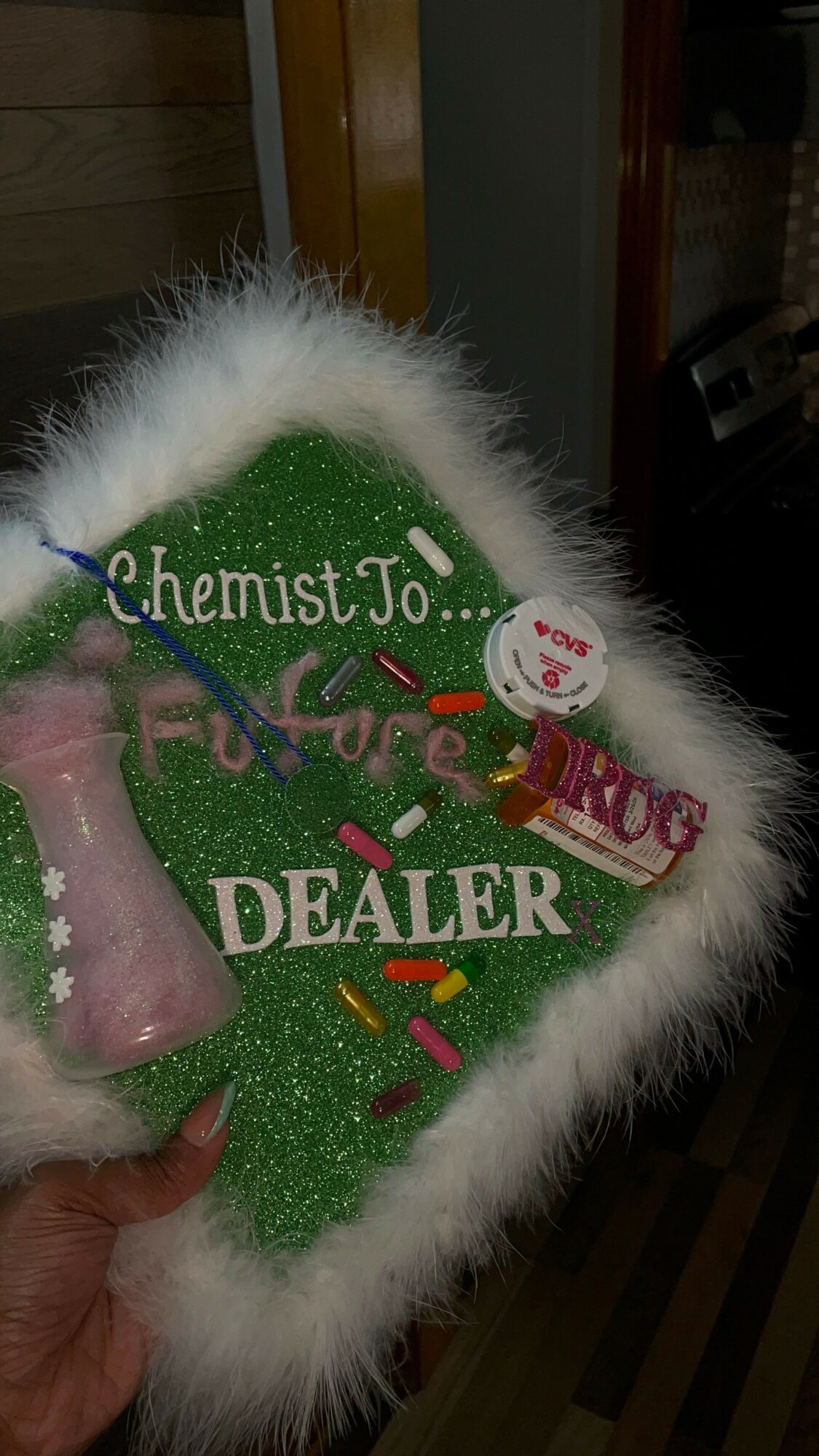 Decorative Christmas-themed sign with green background, white fur border, and colorful text and ornaments.