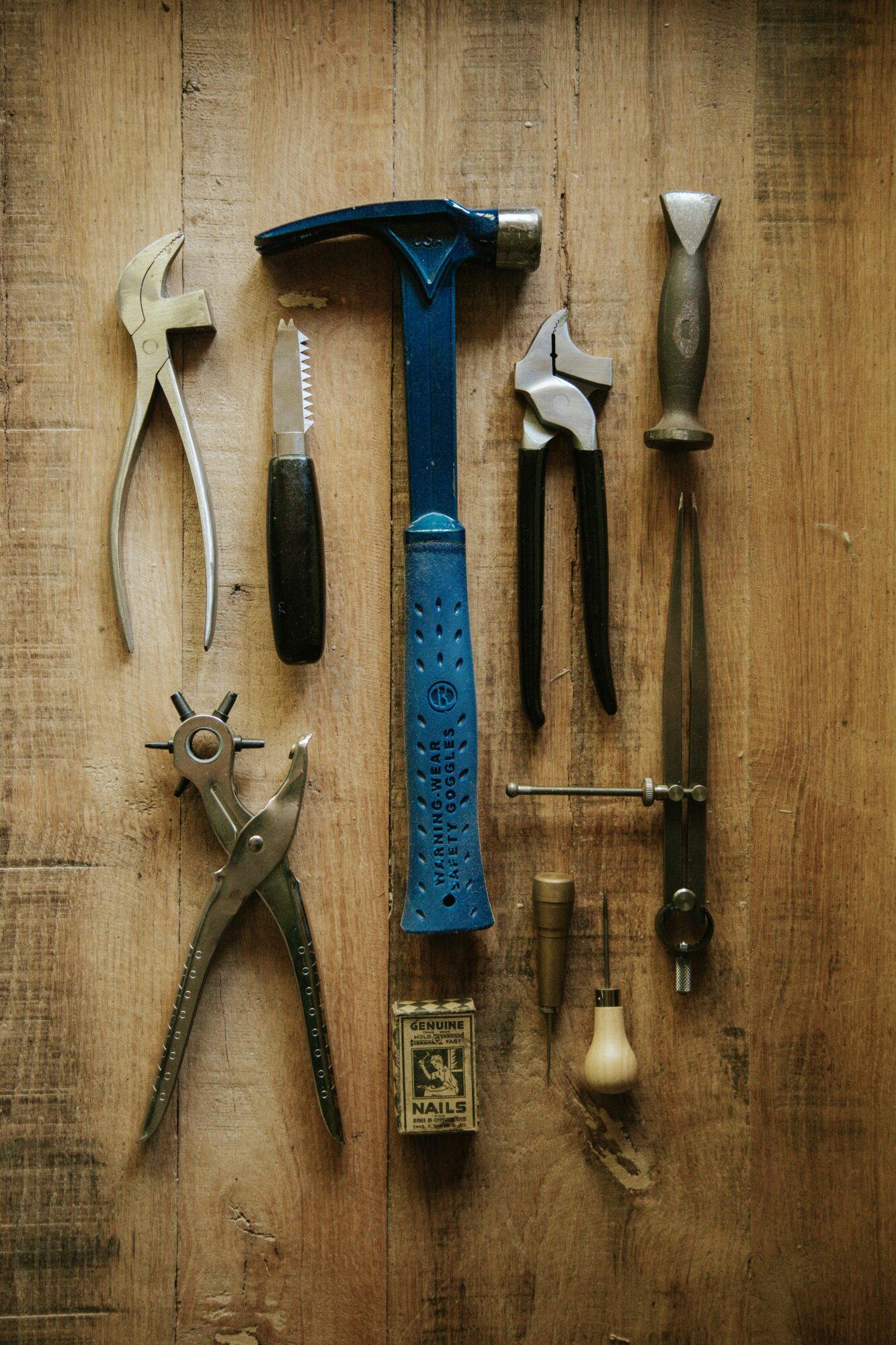 Collection of hand tools including hammers, pliers, and screwdrivers on wooden surface.