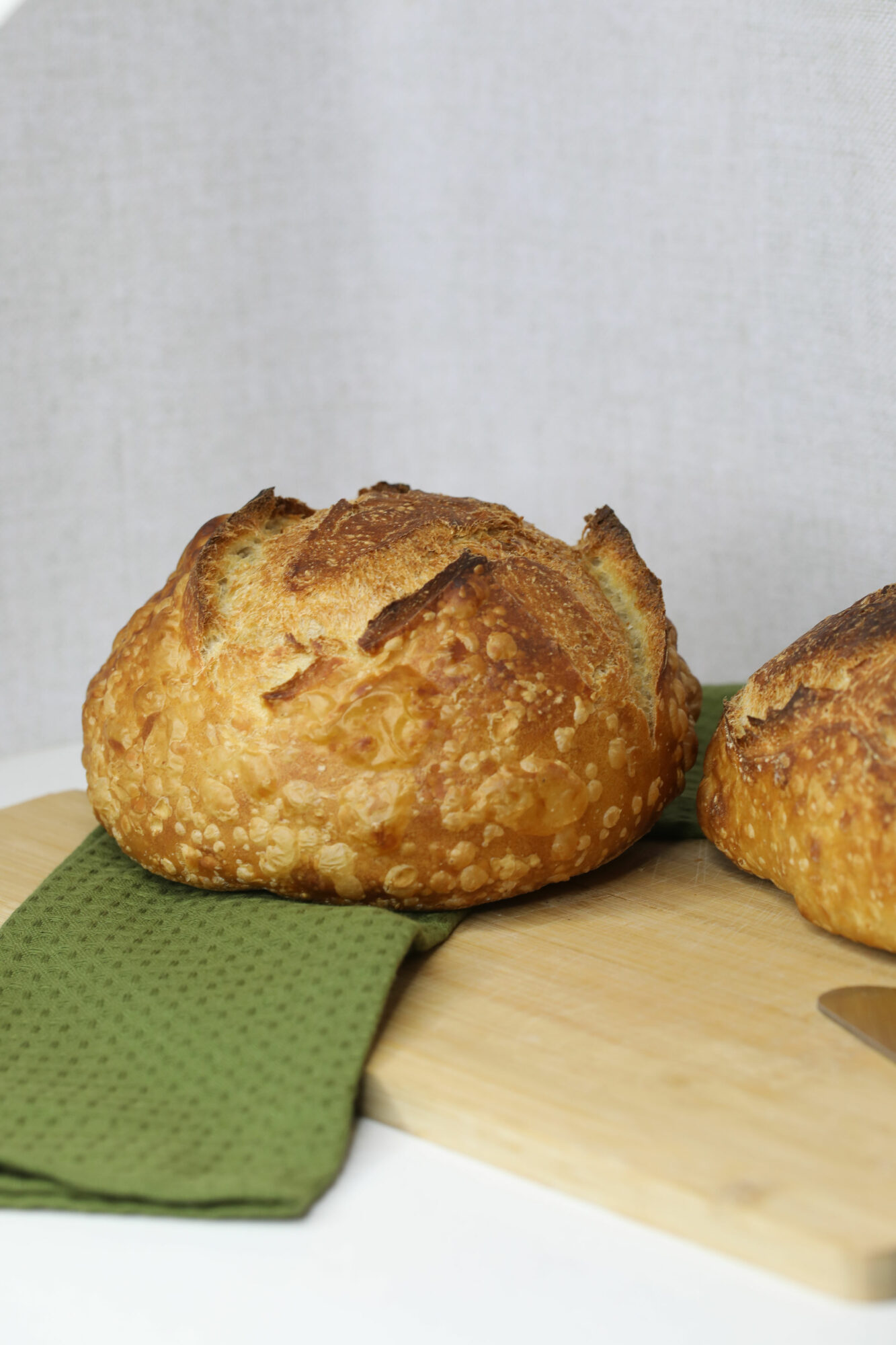 Two golden-brown muffins on a wooden surface with a green cloth, against a light background.