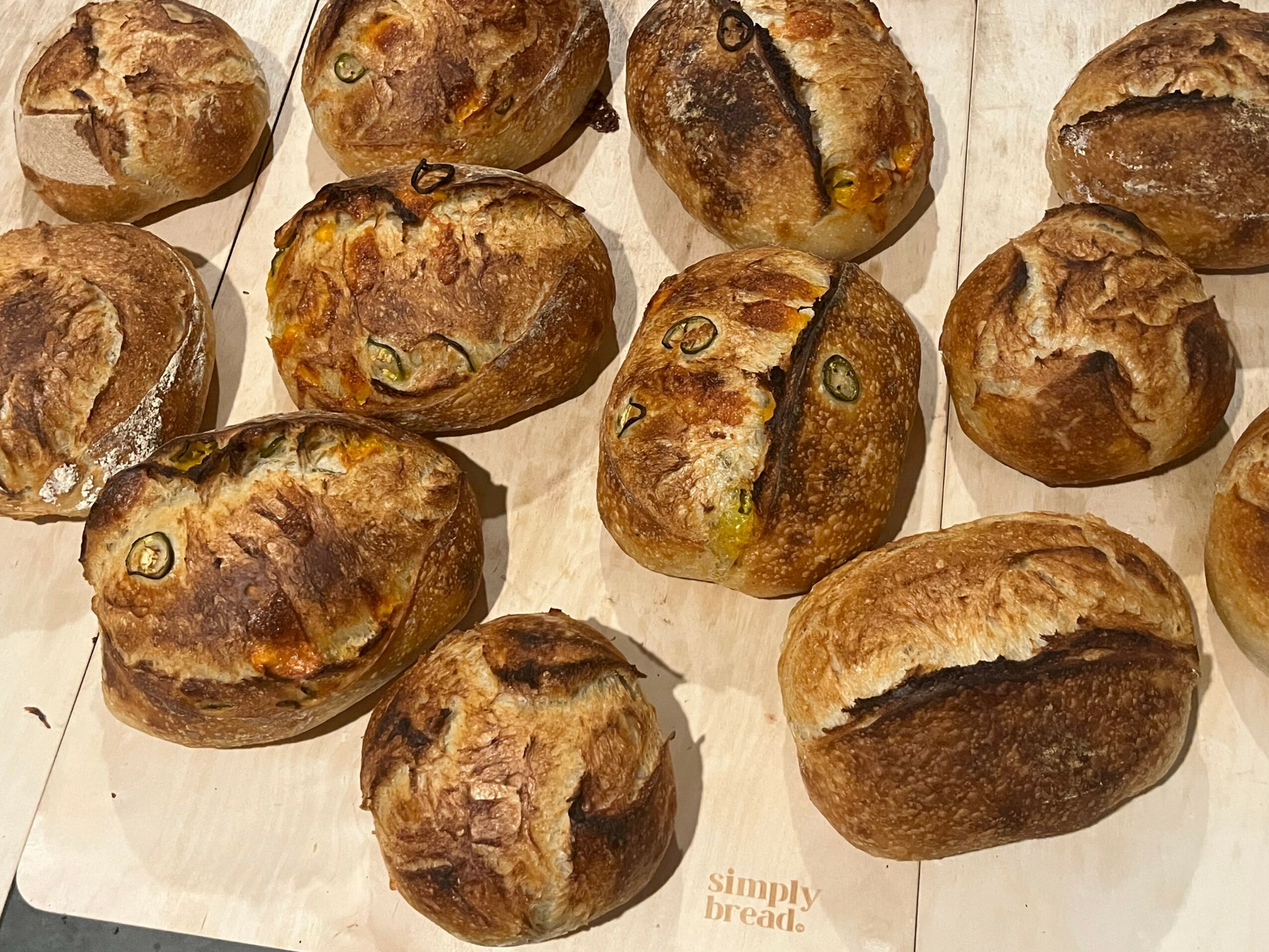 A group of baked bread rolls with a golden-brown crust on a light surface.