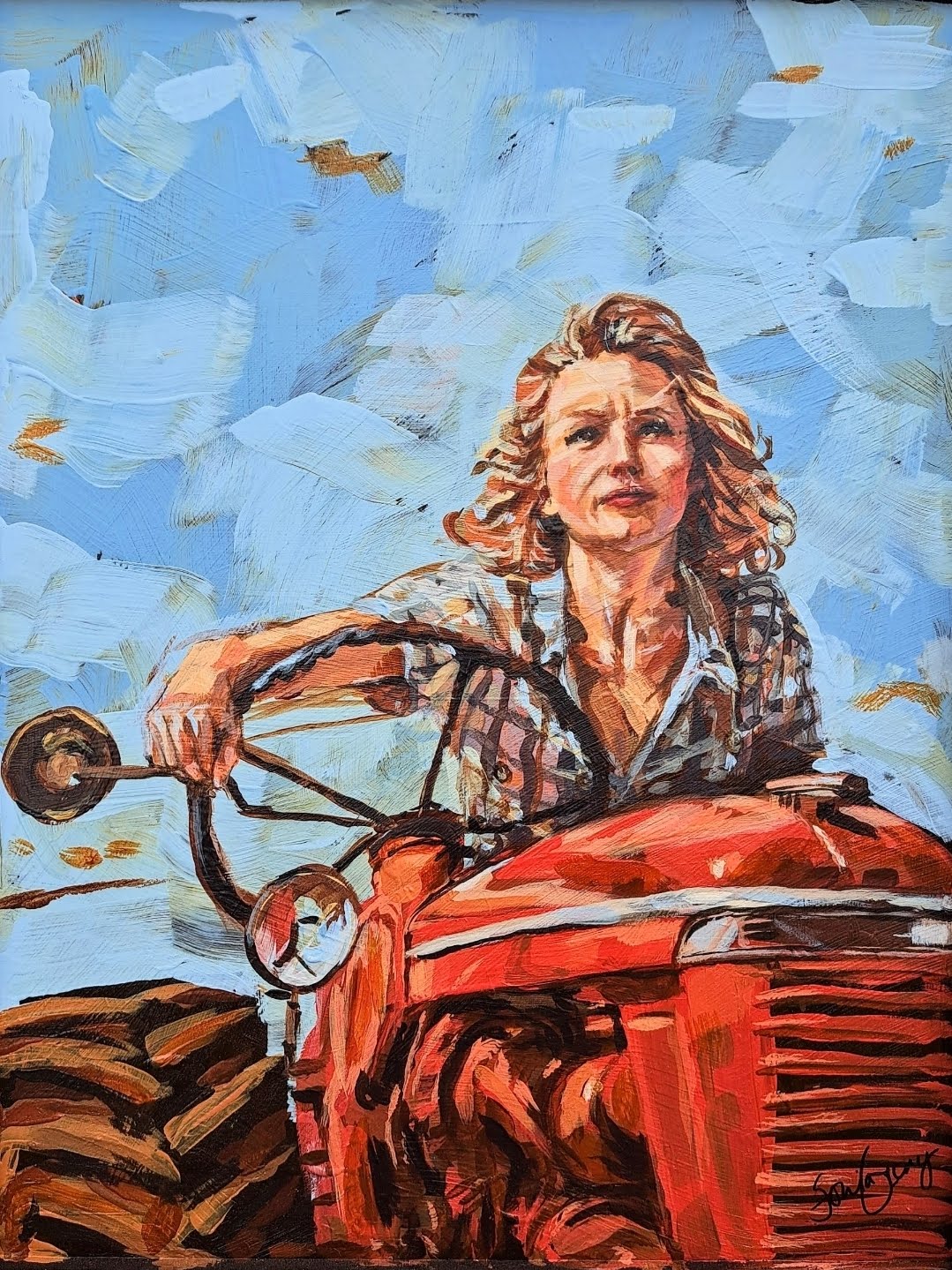 Woman with curly hair driving a red tractor against a blue sky with clouds, holding the steering wheel with one hand.