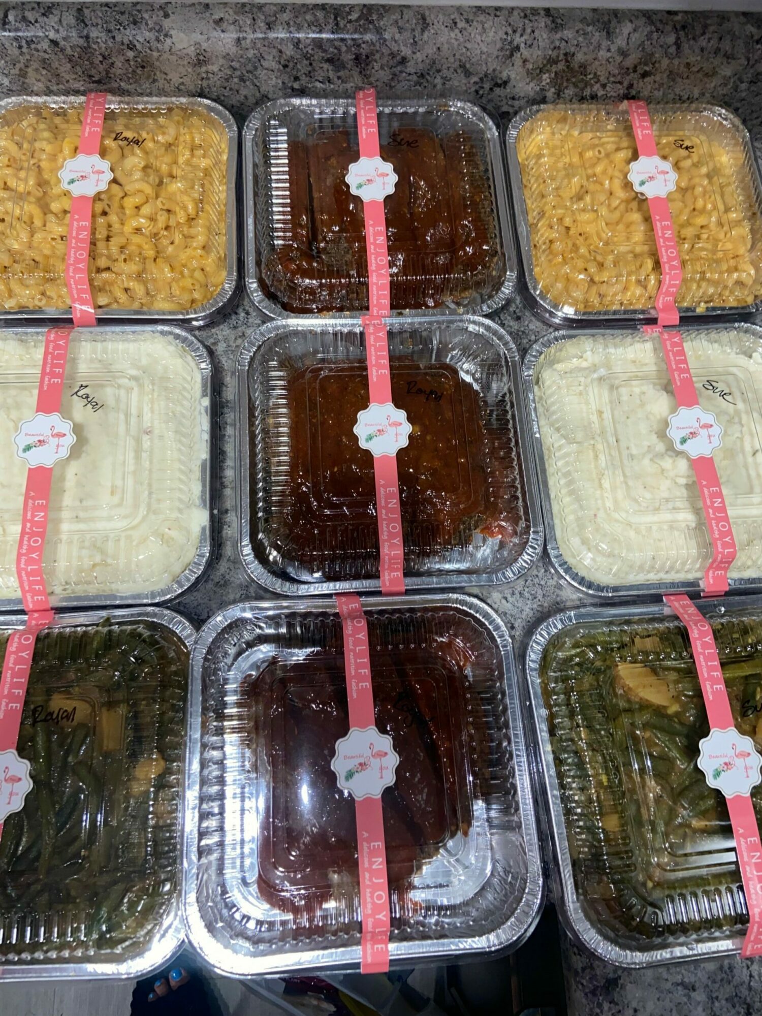 Plastic containers with food items stacked on a surface, some with pink bands around them.