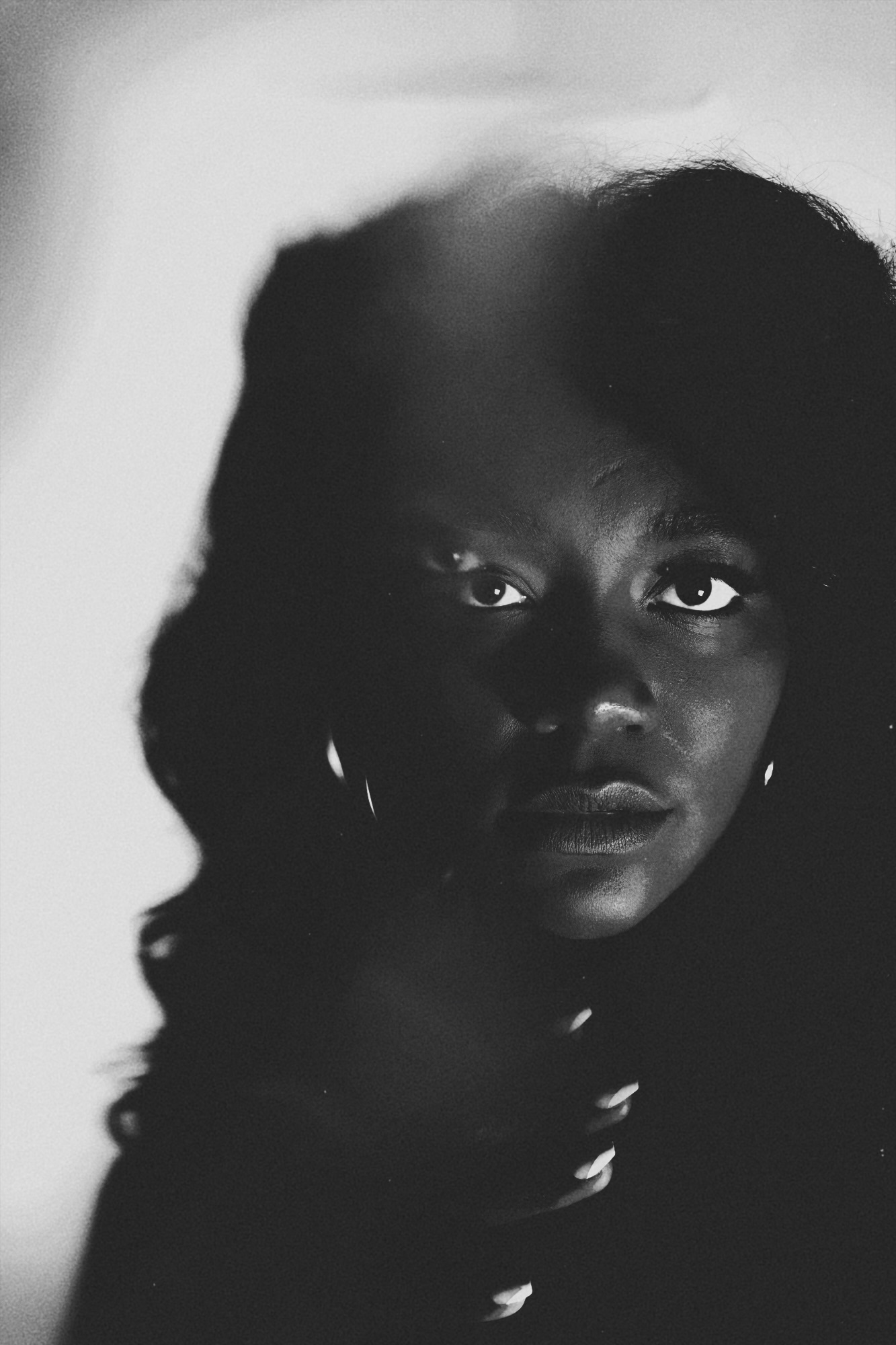 Portrait of a woman with dark hair and earrings, looking directly at the camera, in black and white.